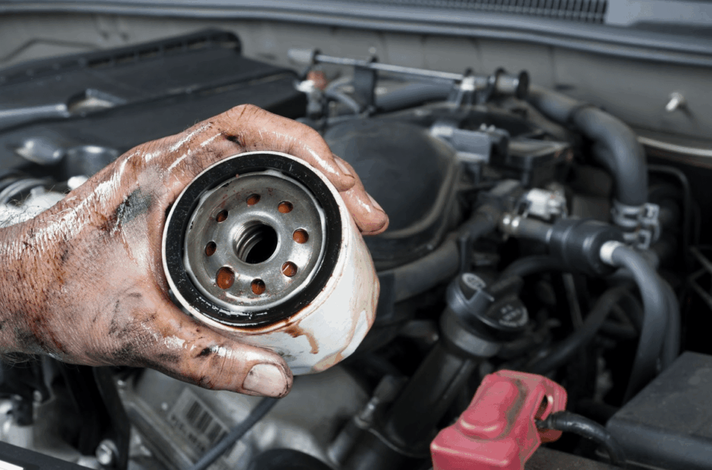 A mechanic shows an old, dirty oil filter just removed from a car during general maintenance