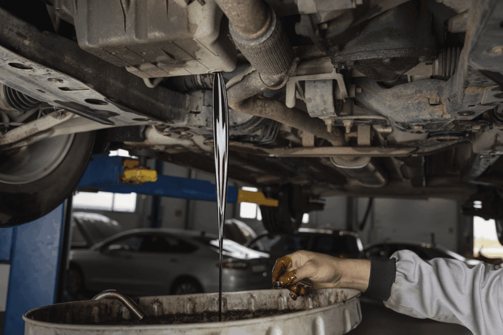 A mechanic drains old used engine oil