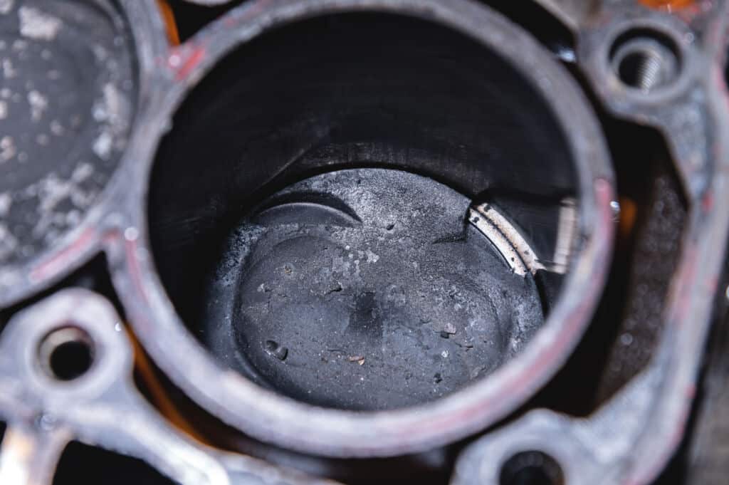 Close-up of a damaged piston of an internal combustion engine with carbon deposits in the cylinder block of a faulty engine.