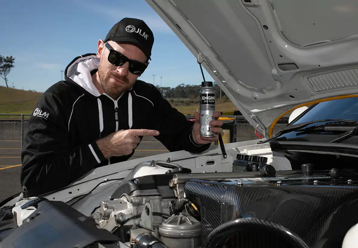 A mechanic holding up a bottle of JLM Engine Oil Flush